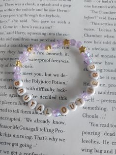 a beaded bracelet with words written in gold and white on top of an open book