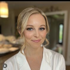 a woman with blonde hair and blue eyes is looking at the camera while wearing a white shirt