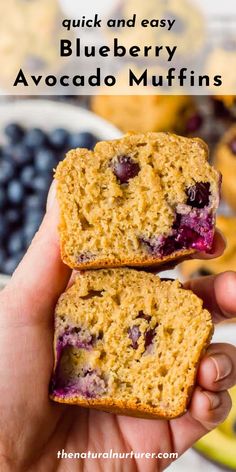 two blueberry muffins are being held up in front of some other muffins