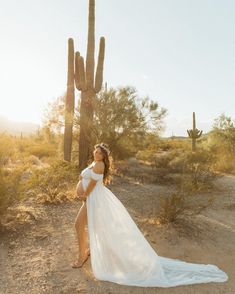 a pregnant woman poses in front of a saguado cactus wearing a wedding dress