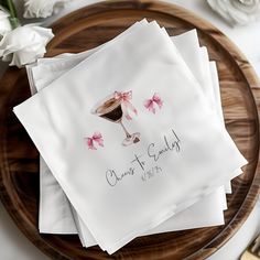 four napkins with pink bows on them are sitting on a wooden plate next to flowers