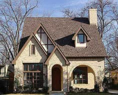 a brick house with two windows and a brown door is shown in the front yard