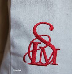 an embroidered monogram on the back of a white shirt with red thread and letters