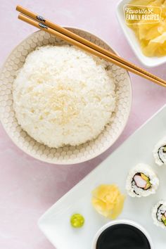 sushi and chopsticks on a white plate next to some pineapple slices