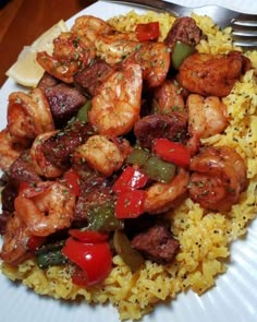 a white plate topped with rice and shrimp next to a fork on top of a table