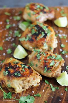 three pieces of chicken with cilantro and lime on a cutting board