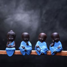 five little buddha statues sitting on top of a wooden rail in front of a dark background