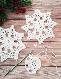 crocheted snowflakes and needles on a wooden table