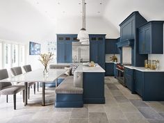 a large kitchen with blue cabinets and white counter tops, along with a dining room table