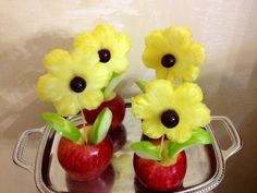 two apples with flowers in them sitting on a silver tray next to an apple vase