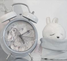 an alarm clock sitting next to a stuffed animal rabbit on a table with a towel around it