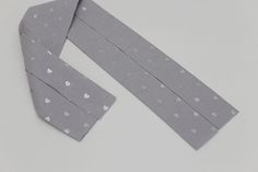 two pieces of gray paper with white hearts on them and one piece cut out to look like a tie