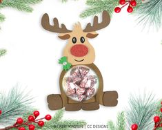 a reindeer ornament with candy in it's mouth, surrounded by pine branches