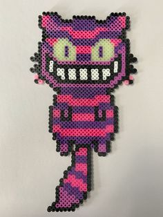 a pink and purple pixel art piece on a white wall with the face of a cat