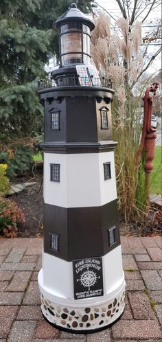 a black and white lighthouse sitting on top of a brick walkway