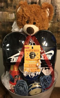 a brown teddy bear sitting in a bucket filled with assorted items