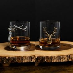 two glasses sitting on top of a wooden table next to each other, one with a deer head