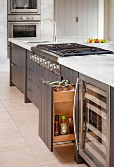 an open cabinet in the middle of a kitchen with stainless steel appliances and marble counter tops