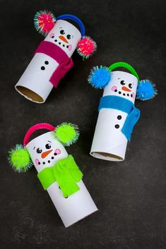 three toilet paper roll snowmen with hats and pom poms on their heads