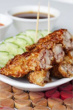 some food is on a white plate with cucumbers and toothpicks in the background