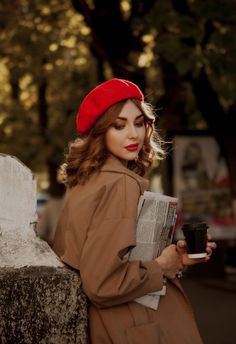 a woman in a red hat is holding a newspaper