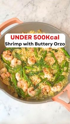 a pan filled with shrimp and vegetables on top of a counter next to a sign that reads under 500kcal shrimp with buttery orzo