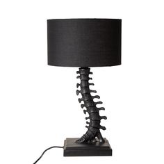 a lamp that has a black shade on it and is shaped like a human leg