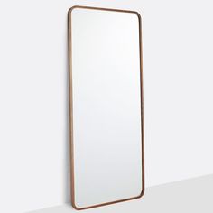 a large mirror hanging on the wall next to a white wall with a wooden frame