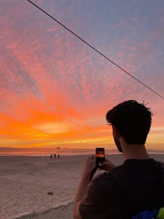 a man taking a photo with his cell phone on the beach at sunset or sunrise