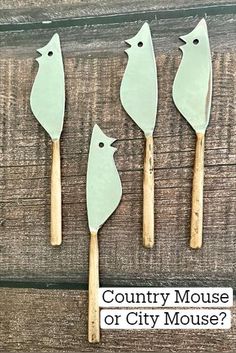 four spatulas with birds on them sitting on a wooden surface