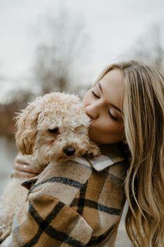 a woman holding a dog in her arms and kissing it's face on the cheek