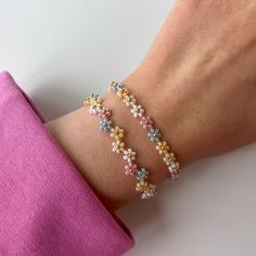 a woman's arm with three bracelets made out of tiny flowers on it