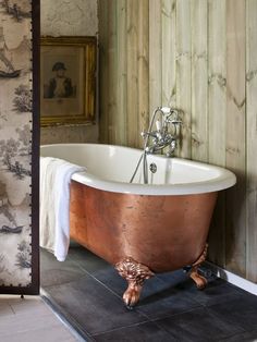 an old fashioned bathtub in a bathroom with wood paneling and wallpaper on the walls