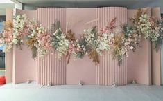 a pink wall decorated with flowers and greenery