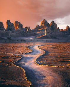 a winding road in the desert with rocks on either side and water running through it