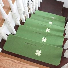 four green envelopes with white flowers on them are sitting on the bannister