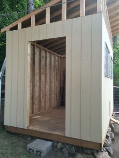 a small shed with the door open and some wood on the ground next to it