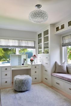 a room with white furniture and windows, including a window seat in the middle of the room