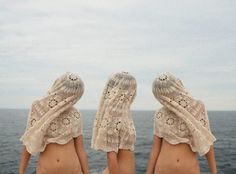 two women sitting on the back of a boat looking out at the ocean with their backs to the camera