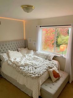 a bedroom with a large bed covered in white blankets and pillows next to a window