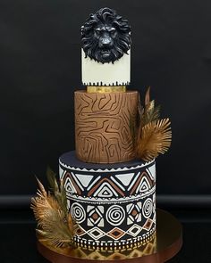 a three tiered cake with a lion head on top and feathers around the edges