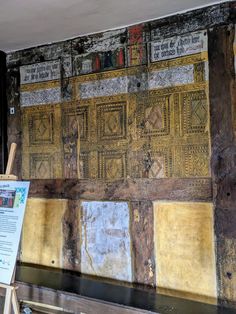 an old wall with some writing on it and a wooden easel next to it