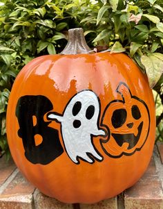 an orange pumpkin decorated with black and white designs on the side, sitting in front of some bushes