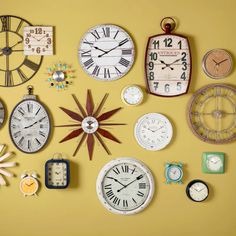 several clocks are arranged on the wall with different shapes and sizes, including one large clock