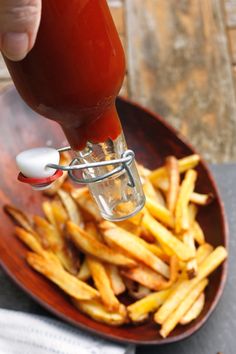 someone is dipping ketchup on some french fries