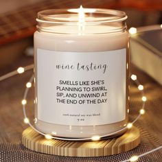 a candle that is sitting on a table with some lights around it and the words, wine tasting smells like she's planning to swrl, sip, and unwind at the end of the day