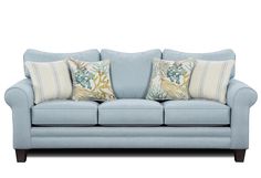 a light blue couch with two pillows on it's back and one pillow sitting on the arm