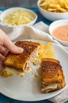 a person holding a grilled cheese sandwich on a plate