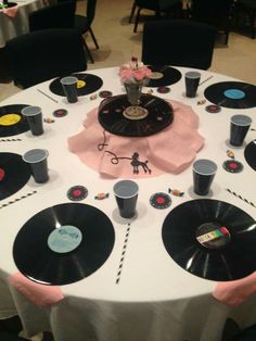 the table is set up with vinyl records and cups on it, along with pink napkins