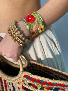 This gorgeous hand embroidered gold cuff bracelet is a bold statement of vintage beauty. This wide gold cuff bracelet features a light mesh fabric embroidered with red, blue, pink and yellow flowers with sparkling gold sequins accents. Add this crafty bracelet to any look! * Embroidered mesh fabric * Handmade in India * Floral thread design with colorful flowers. No item is exactly alike. Measures: 2" wide * Materials: Brass, Embroidered Fabric Boho Bracelets Fabric, Luxury Bohemian Embroidered Jewelry, Unique Handmade Jewelry Fabric, Unique Jewelry Fabric, Luxury Handmade Unique Bracelet, Fabric Jewelry Handmade Inspire Uplift ⭐, Colorful Handbag, Sew Gifts, Pink And Yellow Flowers